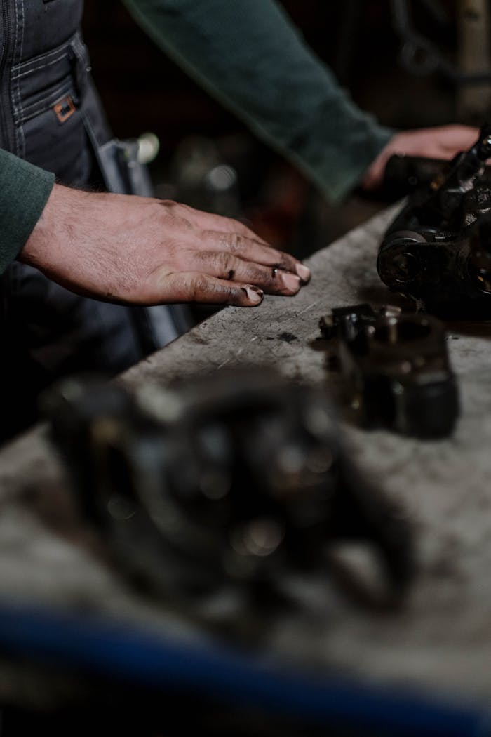 Close-up of a mechanics hands inspecting engine parts in a workshop setting.